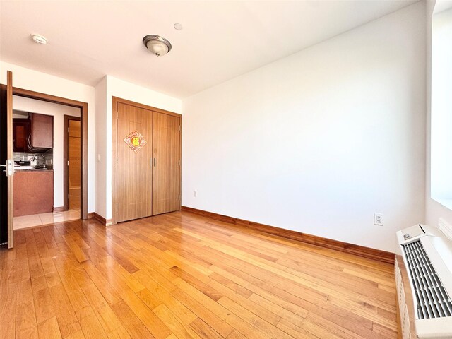 unfurnished bedroom featuring baseboards, a closet, and light wood finished floors