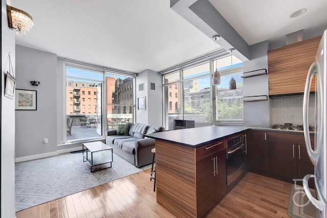 11-24 31st Ave Unit 3A, Astoria, NY 11106 - kitchen featuring stainless steel appliances, wood finished floors, healthy amount of natural light, and a peninsula