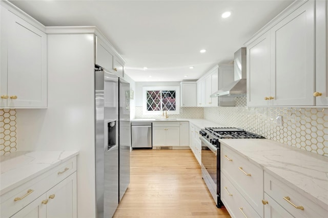 77 Greenwood Ln, White Plains, NY 10607 - kitchen with wall chimney exhaust hood, stainless steel appliances, light wood-style flooring, backsplash, and white cabinetry