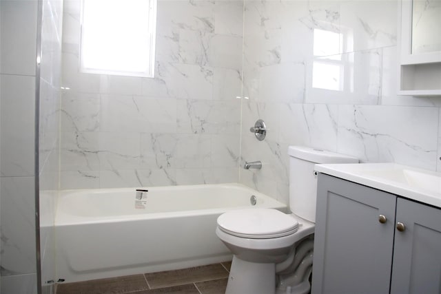 bathroom with vanity, toilet, shower / tub combination, and tile walls