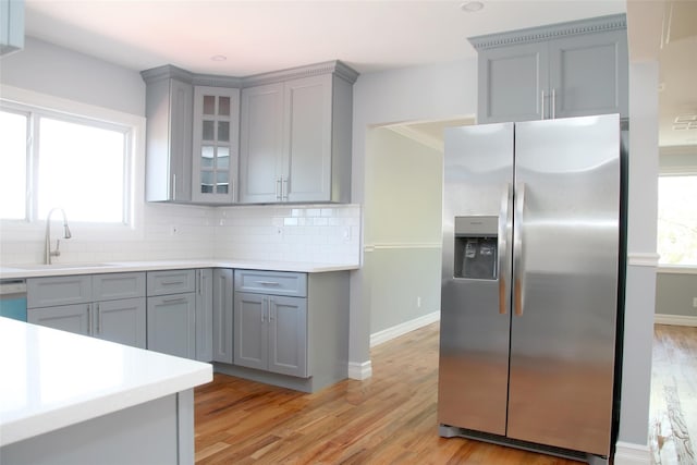 kitchen with a sink, decorative backsplash, gray cabinets, and stainless steel fridge with ice dispenser