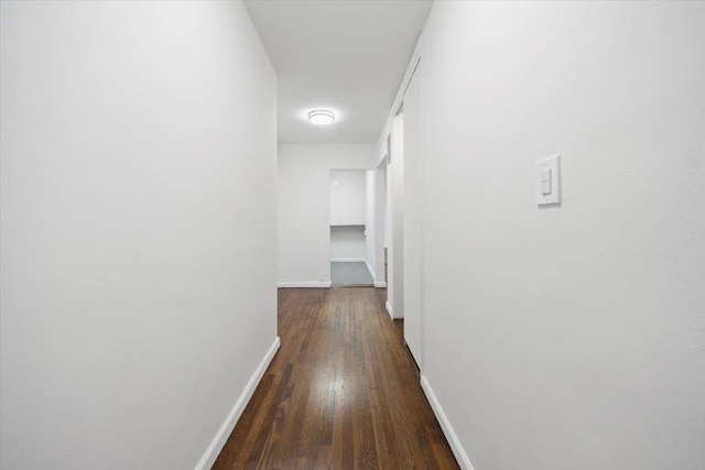 hall with dark wood-style floors and baseboards