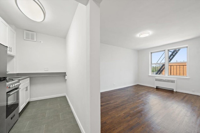 2630 Kingsbridge Ter Unit 5Hi, Bronx, NY 10463 - kitchen with radiator heating unit, stainless steel gas range oven, white cabinets, and baseboards