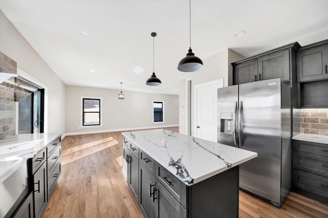 169 Bretton Rd, Yonkers, NY 10710 - kitchen with light stone countertops, stainless steel fridge with ice dispenser, light wood-style flooring, a kitchen island, and pendant lighting