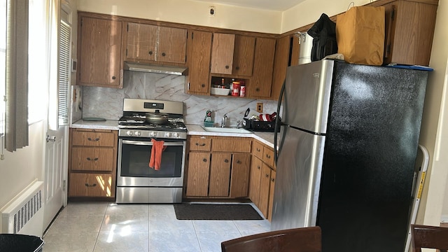 850 First Ave, Franklin Square, NY 11010 - kitchen with appliances with stainless steel finishes, under cabinet range hood, a sink, light countertops, and decorative backsplash