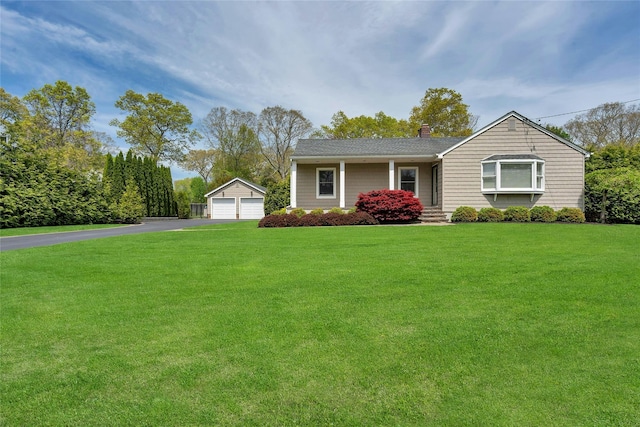 ranch-style home with a chimney, an outbuilding, a front yard, and a garage