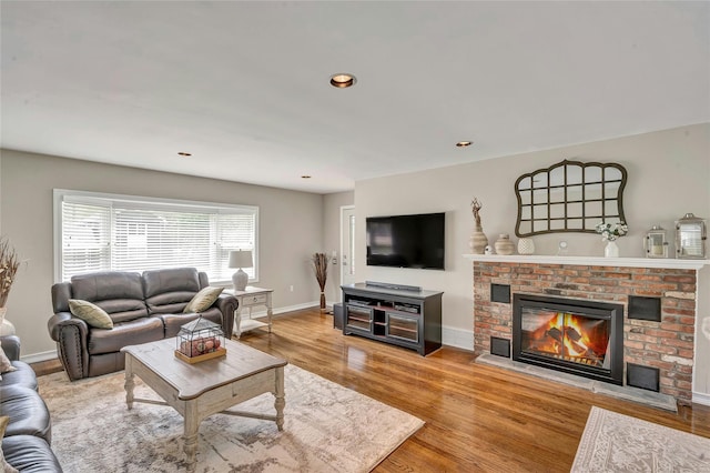 living area with a brick fireplace, recessed lighting, baseboards, and wood finished floors
