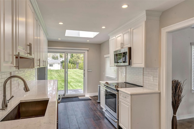 kitchen with baseboards, stainless steel appliances, a skylight, and a sink