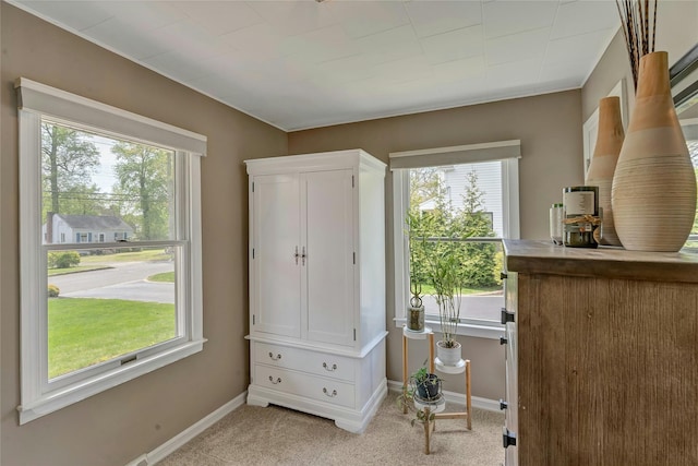 doorway featuring baseboards and light carpet