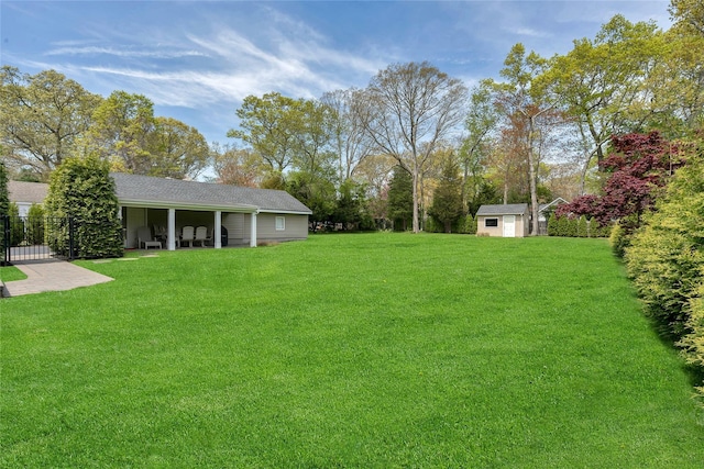 view of yard with fence, an outbuilding, and a shed