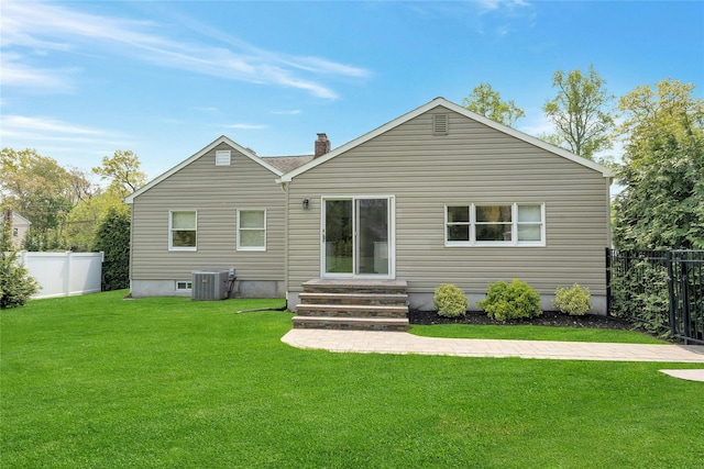 back of property featuring fence, cooling unit, a chimney, entry steps, and a yard
