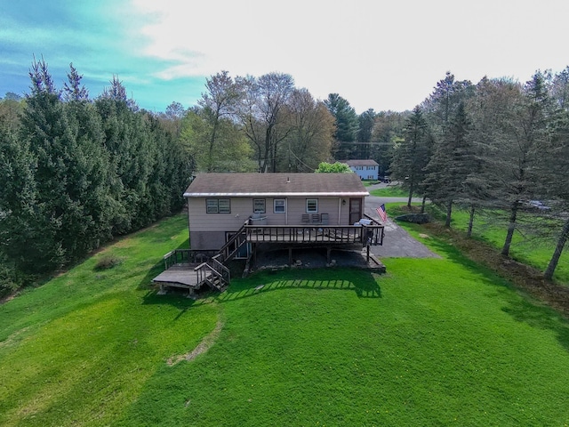 back of property featuring fence, a deck, stairs, a view of trees, and a yard