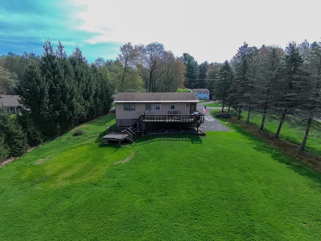 rear view of property with a yard, a wooded view, and a wooden deck