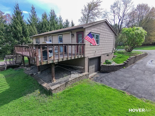 view of front of home with stairs, aphalt driveway, a garage, a wooden deck, and a front yard