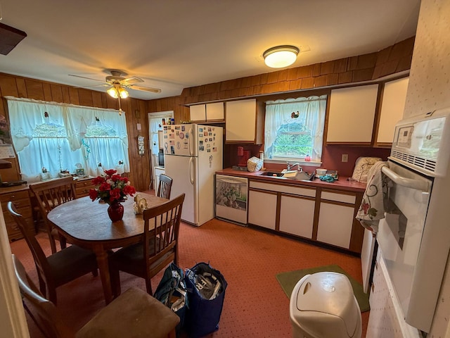 kitchen with white appliances, white cabinets, ceiling fan, and a sink