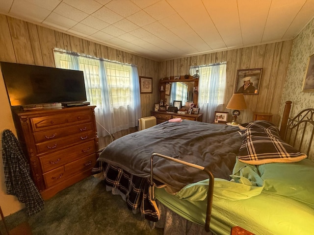 bedroom featuring wooden walls and carpet