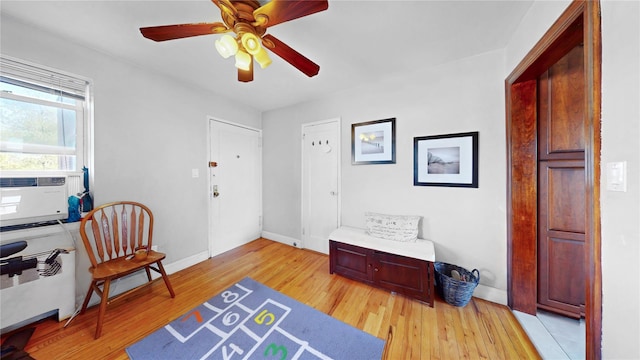 interior space with light wood finished floors, baseboards, a ceiling fan, and cooling unit