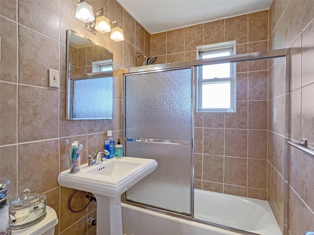 bathroom with tile walls, toilet, and enclosed tub / shower combo