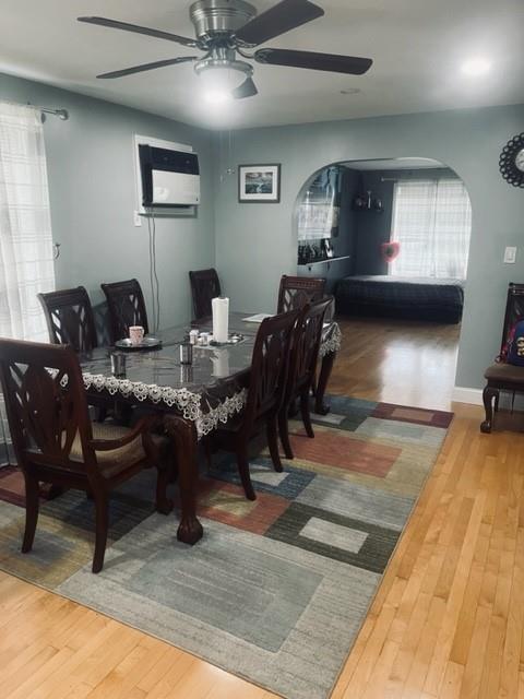 dining room featuring arched walkways, a ceiling fan, and wood finished floors