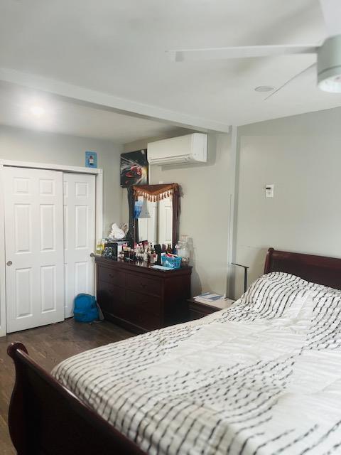 bedroom featuring a closet, wood finished floors, and an AC wall unit