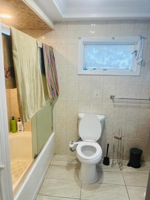 bathroom with tile walls, toilet, ornamental molding, tile patterned floors, and bathing tub / shower combination