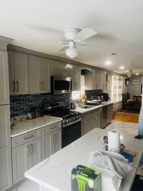 kitchen featuring a sink, stainless steel appliances, tasteful backsplash, and gray cabinets
