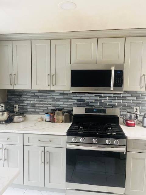 kitchen featuring stainless steel appliances, light stone counters, and backsplash