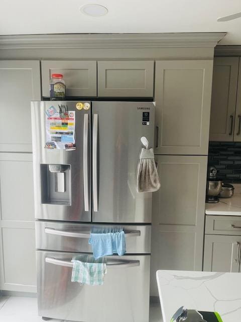 kitchen featuring stainless steel fridge with ice dispenser, gray cabinets, light stone counters, and tasteful backsplash