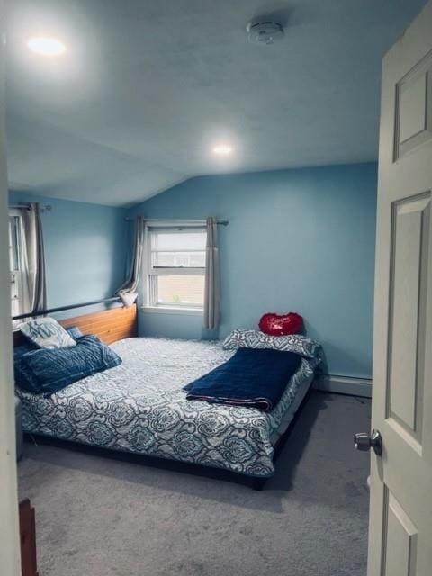 bedroom featuring a baseboard heating unit, carpet flooring, and vaulted ceiling