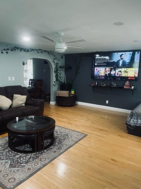 living room with arched walkways, baseboards, ceiling fan, and wood finished floors