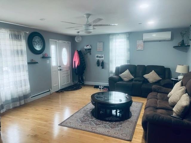 living area with ceiling fan, a wall unit AC, and wood finished floors
