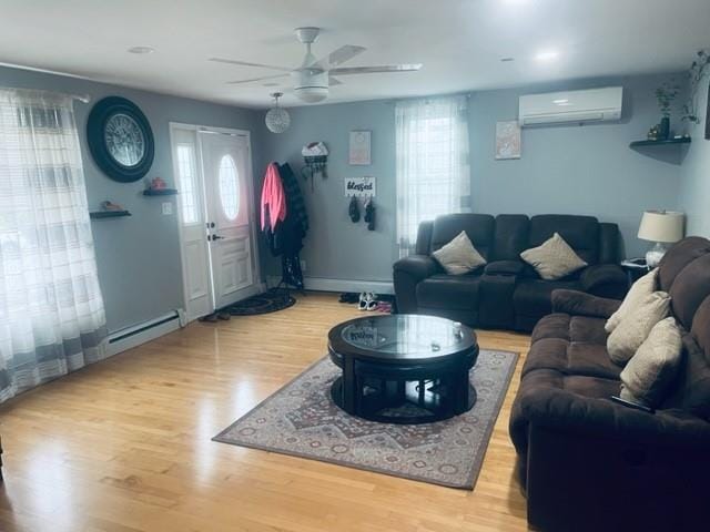 living area with a baseboard heating unit, a wall mounted AC, a ceiling fan, and wood finished floors