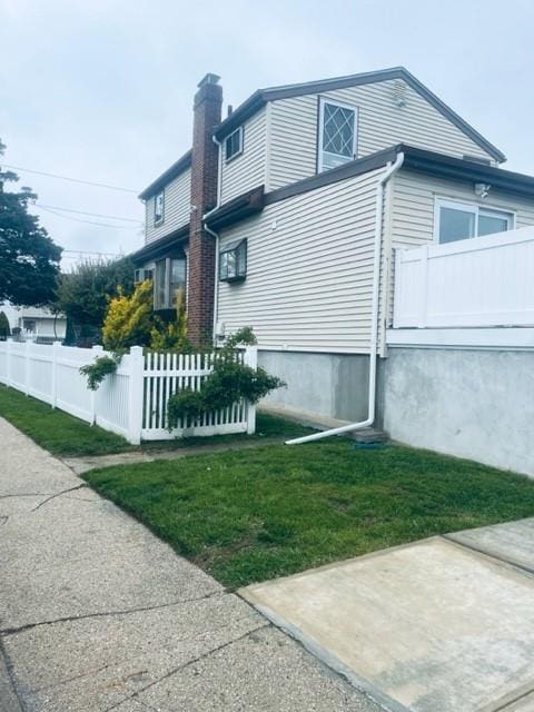 view of side of property with a yard, a chimney, and fence
