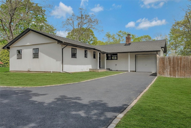 ranch-style house featuring a garage, a front lawn, aphalt driveway, fence, and a chimney