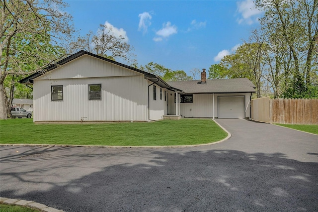 single story home with a front lawn, aphalt driveway, fence, a chimney, and an attached garage