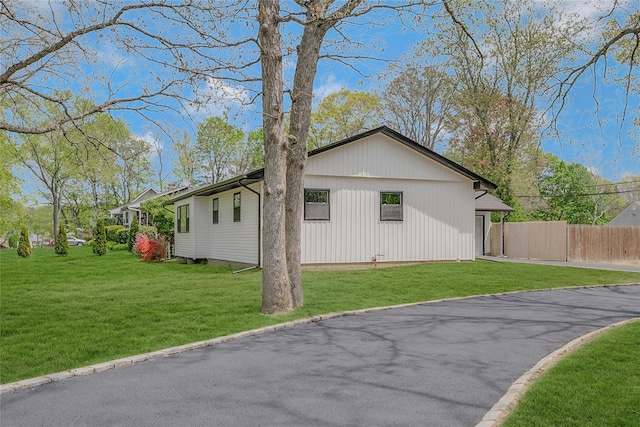 view of side of home featuring a lawn and fence