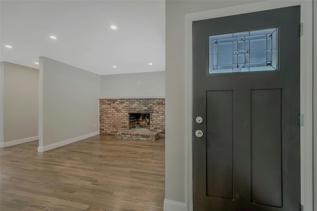 entryway featuring baseboards, a brick fireplace, recessed lighting, and wood finished floors