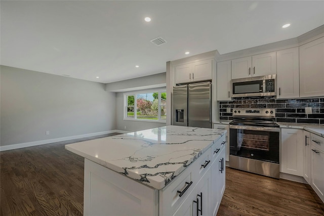 kitchen with visible vents, appliances with stainless steel finishes, light stone countertops, and a center island
