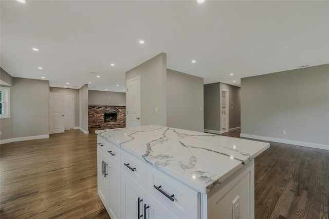 kitchen featuring open floor plan, dark wood-type flooring, a center island, white cabinetry, and light stone counters