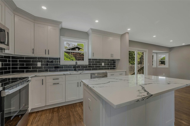 kitchen featuring decorative backsplash, a kitchen island, appliances with stainless steel finishes, a sink, and dark wood-style floors