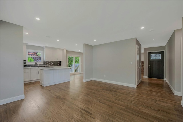 kitchen with backsplash, wood finished floors, light countertops, baseboards, and white cabinets