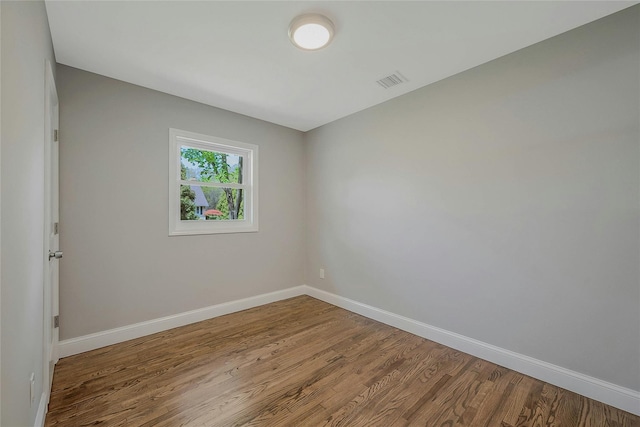empty room featuring baseboards, wood finished floors, and visible vents