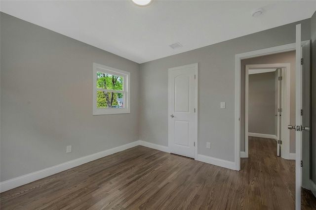 unfurnished bedroom featuring baseboards, dark wood finished floors, and visible vents