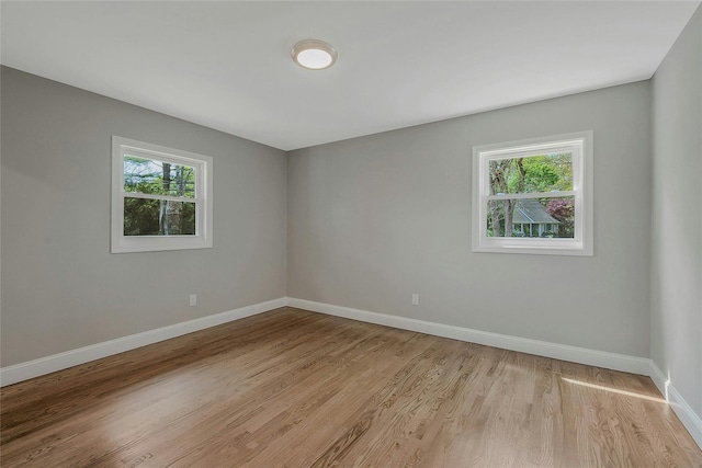 spare room with baseboards and light wood-type flooring