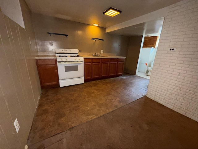 kitchen featuring light countertops, white range with gas stovetop, brown cabinets, and a sink