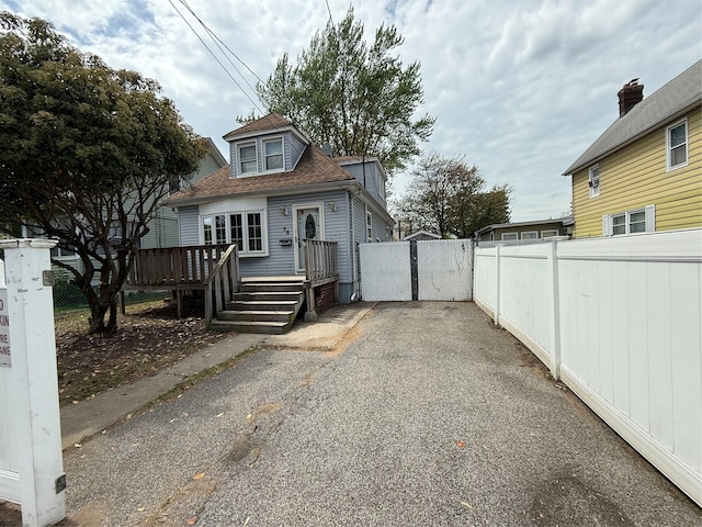 view of side of property featuring a deck, fence, and roof with shingles