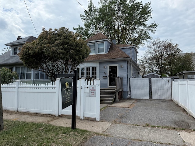 bungalow-style home with a gate, a shingled roof, and a fenced front yard