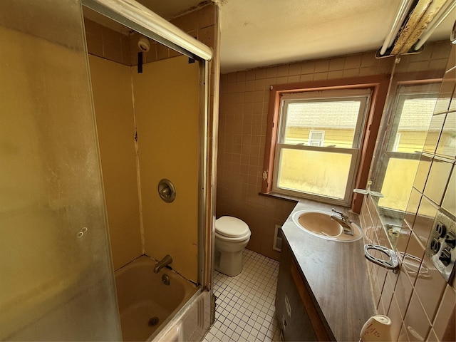 full bathroom featuring vanity, toilet, tile patterned floors, enclosed tub / shower combo, and tile walls