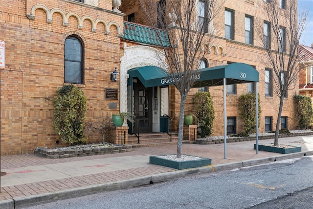 property entrance featuring brick siding and a balcony
