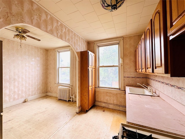 68-11 52nd Dr, Maspeth, NY 11378 - kitchen featuring radiator, a sink, healthy amount of natural light, a ceiling fan, and wallpapered walls